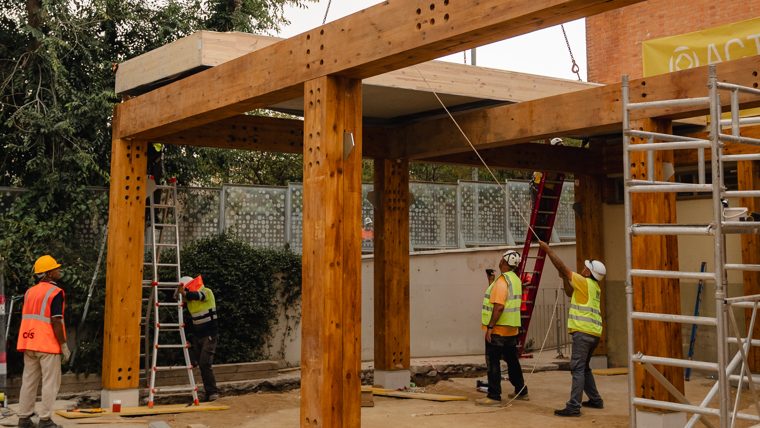 Una grua col·loca una de les peces de fusta de l'estructura de l'ampliació de l'escola bresso municipal La Mar